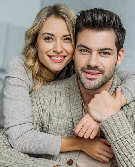 Man in sweater hugged from behind by blonde woman