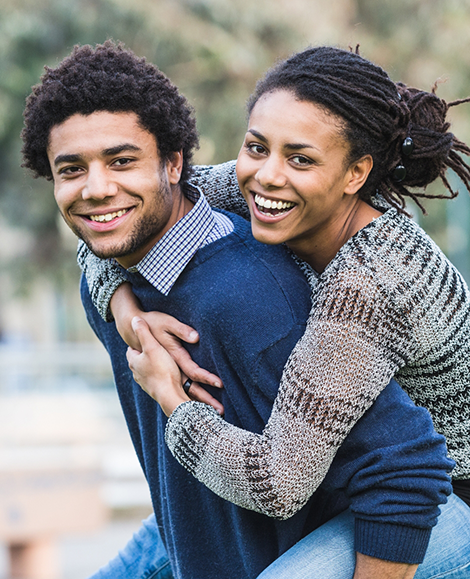 Smiling man giving smiling woman a piggyback ride