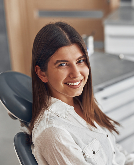 Female dental patient in treatment chair looking to side and smiling