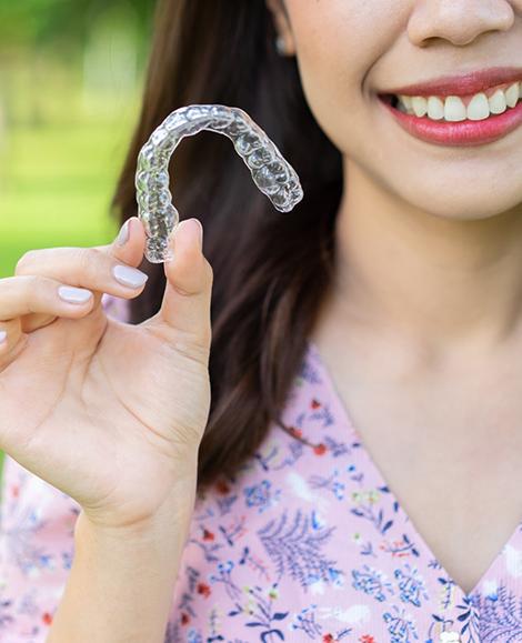 Woman holding Invisalign clear aligner in Parma