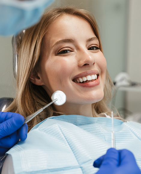 Blonde woman smiling at dental instruments used for preventive dentistry in Parma