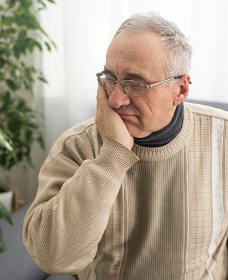 Man in sweater rubbing jaw in pain